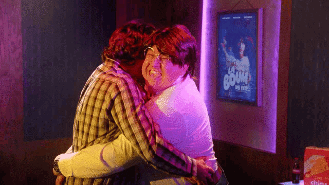 a man and woman hugging in front of a sign that says boom