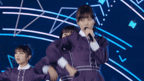 a woman singing into a microphone with a blue background