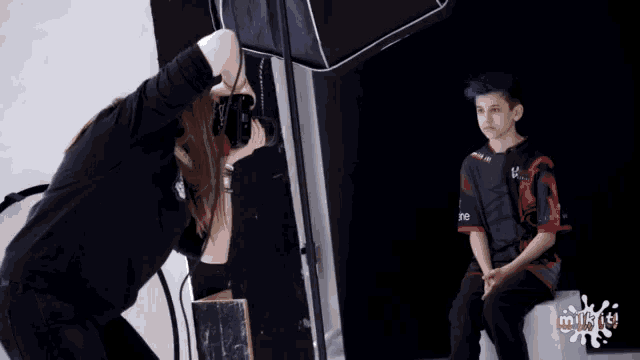 a woman is taking a picture of a boy wearing a shirt that says milkies