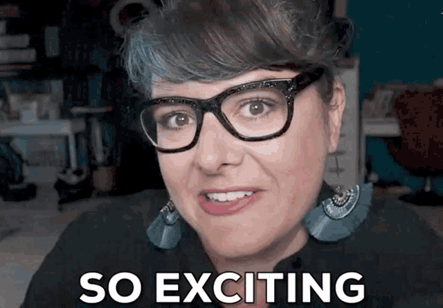 a woman wearing glasses and earrings smiles with the words so exciting behind her