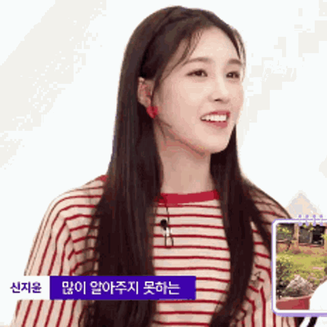 a woman in a red and white striped shirt is smiling in front of a sign that says ' a ' on it