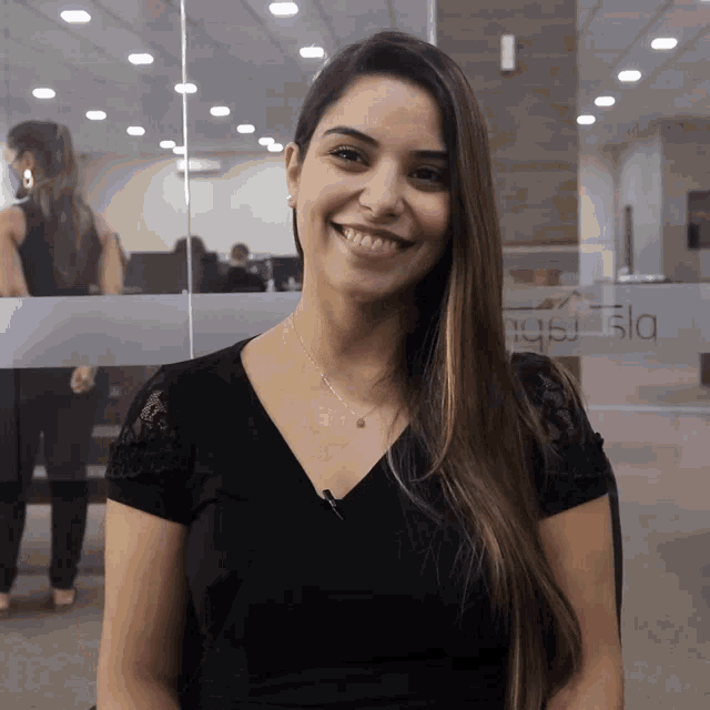 a woman in a black shirt smiles in front of a glass wall that says ' nsla ' on it