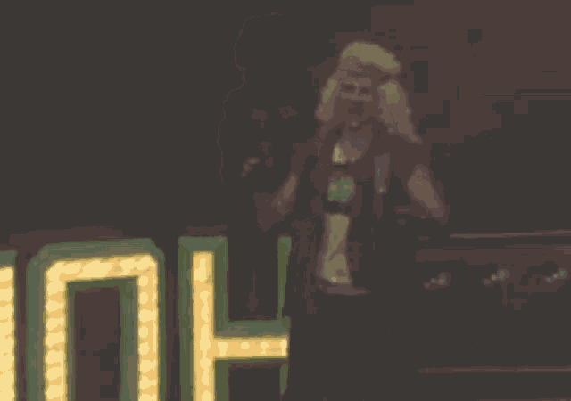a blurry picture of a man in a wig standing in front of a sign that says oh