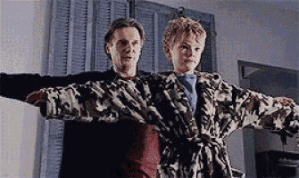 a man and a boy are standing next to each other with their arms outstretched in a room .