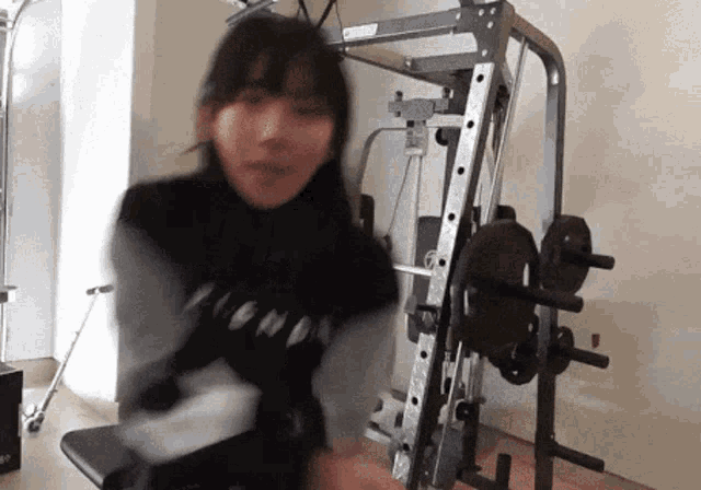 a woman is standing in front of a gym machine with a black shirt that says ' i love ' on it