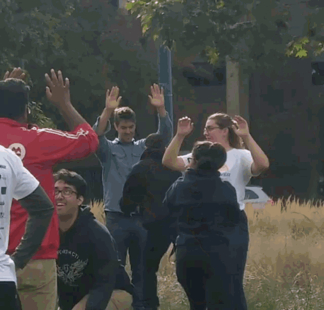 a group of people are standing in a circle with their hands in the air .