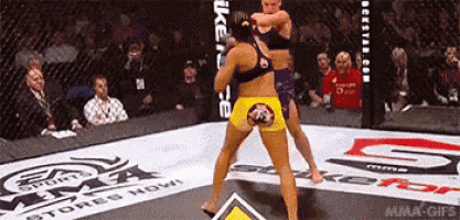 two women are fighting in a ring that has mma stores now written on it