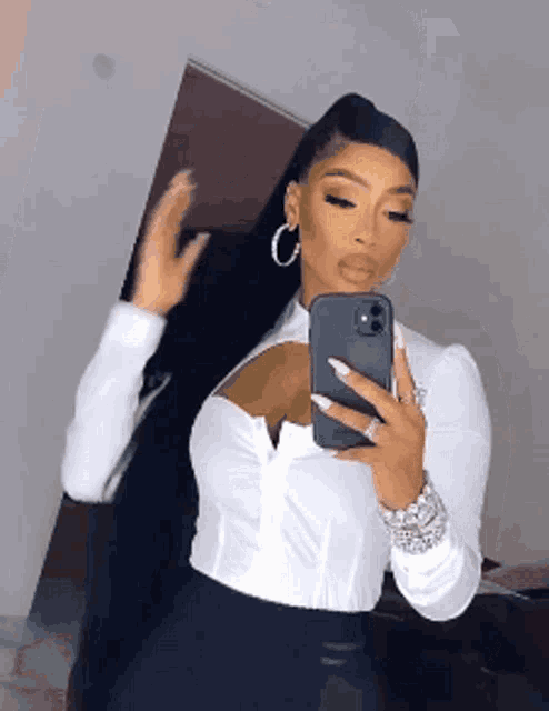a woman is taking a selfie in front of a mirror .