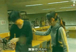 a man and a woman are standing in a room with yeah written on the screen