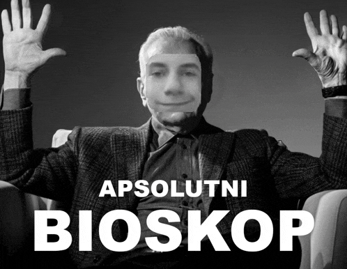 a black and white photo of a man with his hands in the air and the words apsolutni bioskop behind him