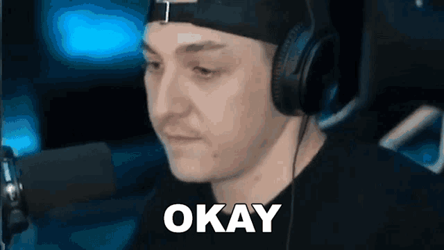 a man wearing headphones is sitting in front of a microphone and saying okay .