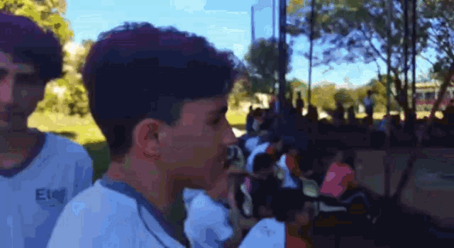 a boy wearing a shirt that says eleo stands in front of a crowd of people