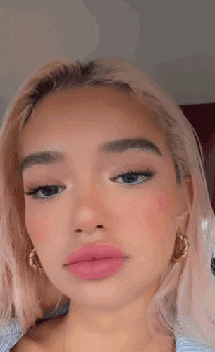 a close up of a woman 's face with pink lipstick on her lips and blue eyes .