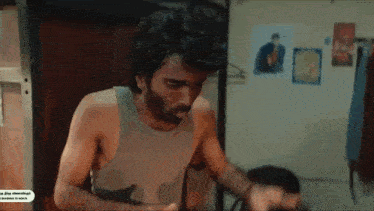 a man without a shirt is standing in a room with his hands on his head
