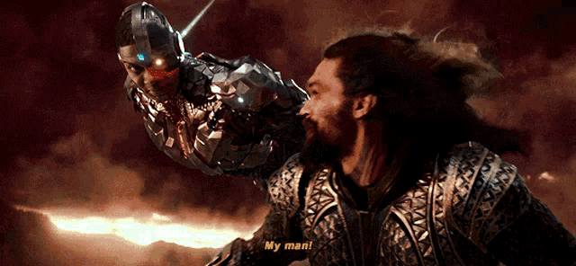 a man with a beard is standing next to a robot and says my man