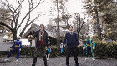 a man in a suit and tie stands next to a group of superheros