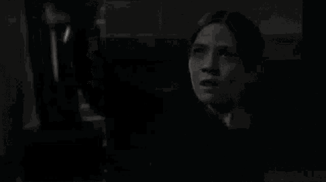 a black and white photo of a woman looking up in a room .