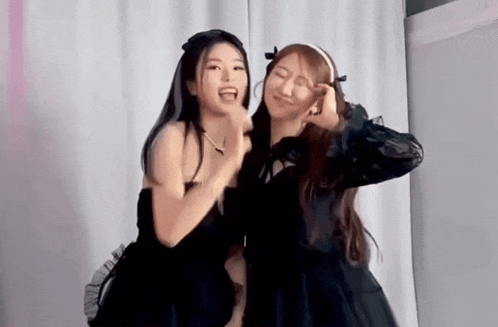 two girls in black dresses are standing next to each other and making funny faces .