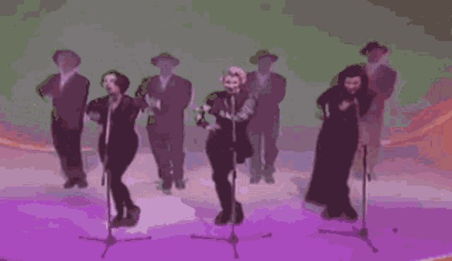 a group of people are singing into microphones on a stage