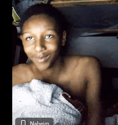 a shirtless boy is smiling with the name naheim in the bottom right corner