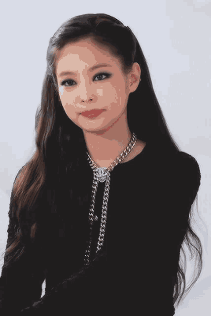 a woman wearing a black shirt and a necklace with a chanel logo