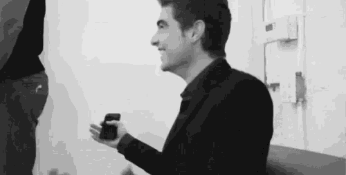 a black and white photo of a man holding a cell phone .