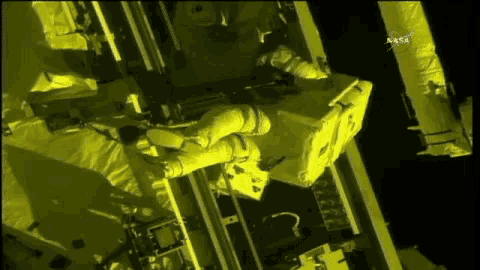 a man in a space suit is working on a piece of equipment with nasa in the background