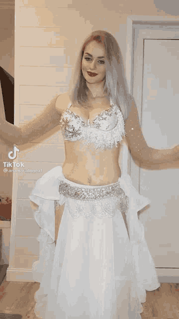 a woman in a white belly dancer costume is dancing .
