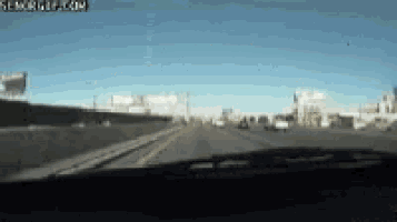 a car is driving down a highway with a sign that says searchgif.com on it