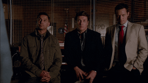 three men are sitting in front of a wall that says nypd