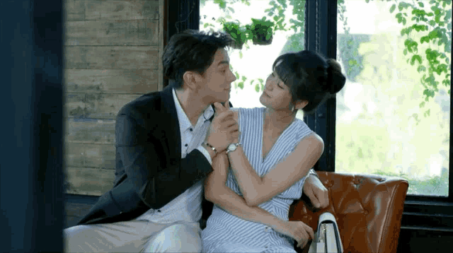 a man and a woman are sitting on a couch and the woman is wearing a watch