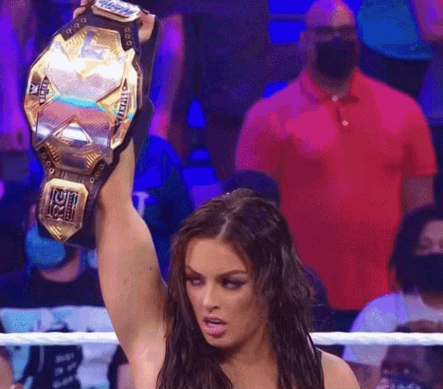 a woman in a wrestling ring holds up a championship belt that says wwe
