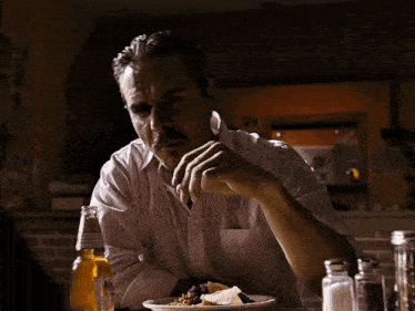 a man sits at a table with a plate of food and a bottle of corona