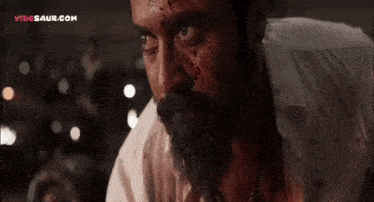 a man with a beard and blood on his face is looking at the camera