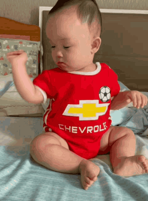 a baby wearing a red shirt that says chevrole on it