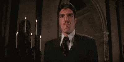 a man in a suit and tie with a mustache is making a funny face .