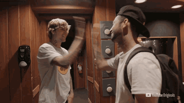 two men giving each other a high five in an elevator with youtube originals written on the bottom