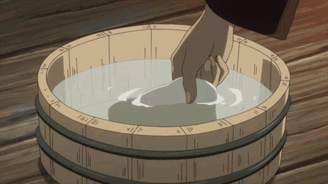 a person 's hand is reaching into a wooden bucket with numbers on it