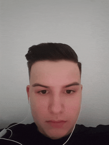 a young man wearing headphones looks at the camera with a serious look on his face