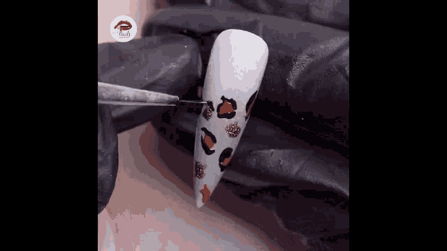 a woman is painting a leopard print on her nails .