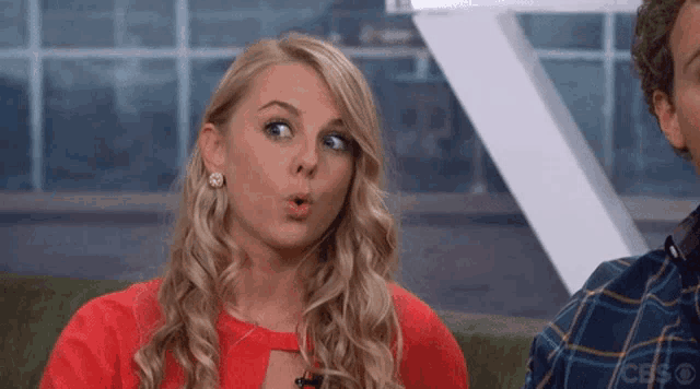 a woman with a surprised look on her face is wearing a red top