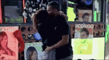 a man and woman are hugging in front of a sign that says rodrigo on it