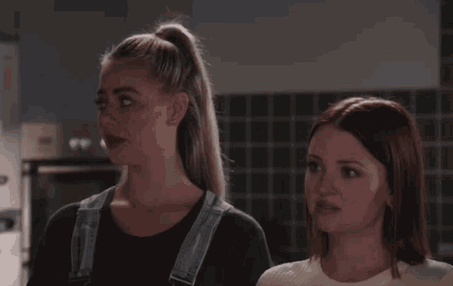 two women are standing next to each other and looking at something