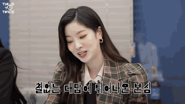 a woman wearing a plaid jacket and earrings is smiling and talking in korean