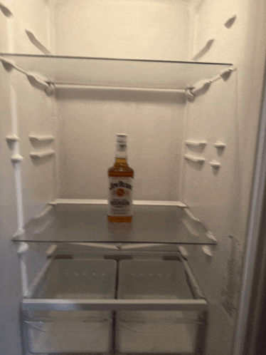 a bottle of jim beam bourbon sits on a glass shelf in an empty refrigerator