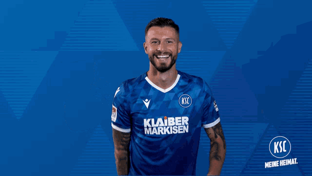a man in a blue shirt that says ksc on it is holding a red card
