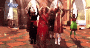 a group of people are dancing in a room with a disney logo in the background