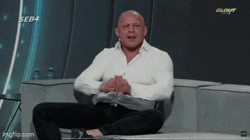 a man in a white shirt is sitting on a couch with his legs crossed in front of a screen that says seb4