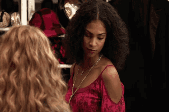 a woman with curly hair is wearing a red top and necklace