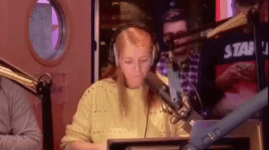 a woman wearing headphones is sitting in front of a microphone in a radio station .
